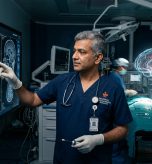 Senior Indian neurosurgeon examining 3D holographic brain scan and cranial MRI in advanced operating room